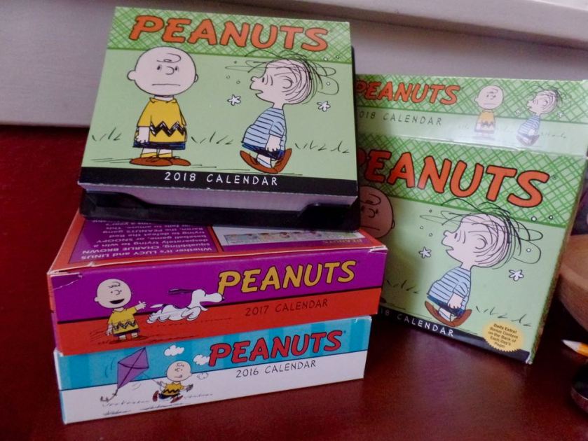 The Peanuts 2018 page-a-day calendar, sitting atop my boxes of the 2017 and 2016 calendars too.