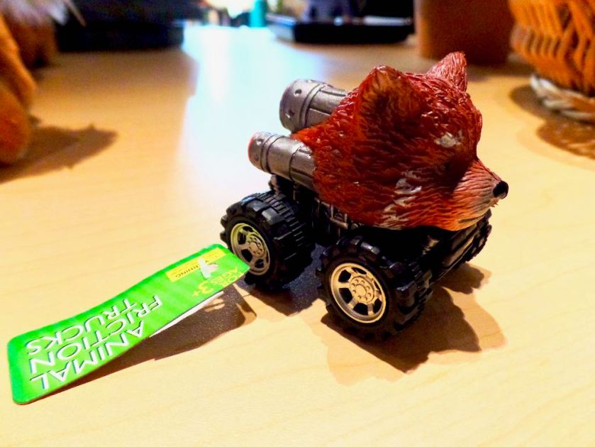 Gift shop toy: an 'Animal Friction Truck', an inch-long miniature monster truck toy in which the front half of the 'truck' is shaped and painted like a red panda's head.