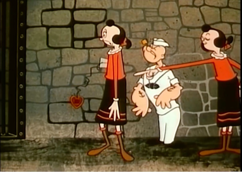 Olive Oyl pointing an accusatorial finger at her robot duplicate, who's turned away, frowning, with its heart dangling sadly on a long spring. Popeye looks on at the confrontation.